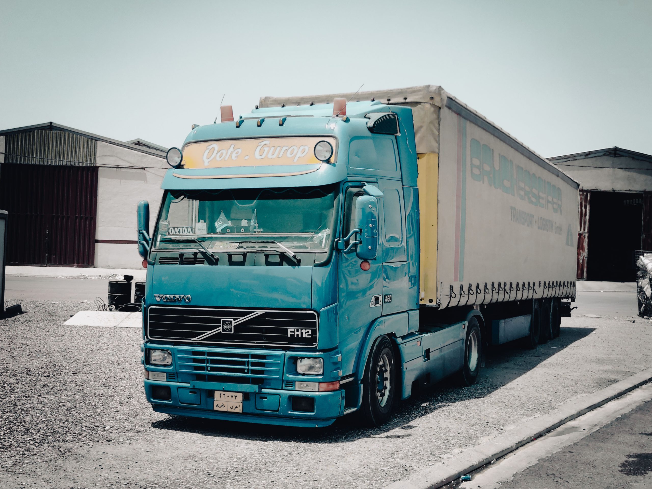 Camion bleu Volvo devant entrepôt industriel