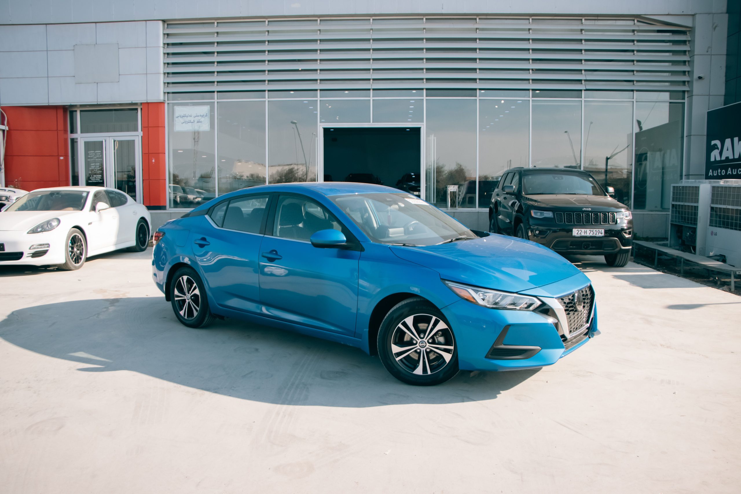 Nissan Sentra bleue devant concessionnaire ensoleillé