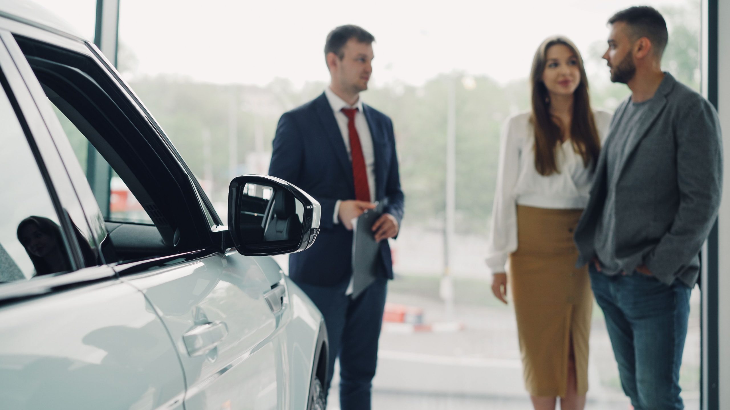 Vendeur conseillant un couple dans un showroom automobile