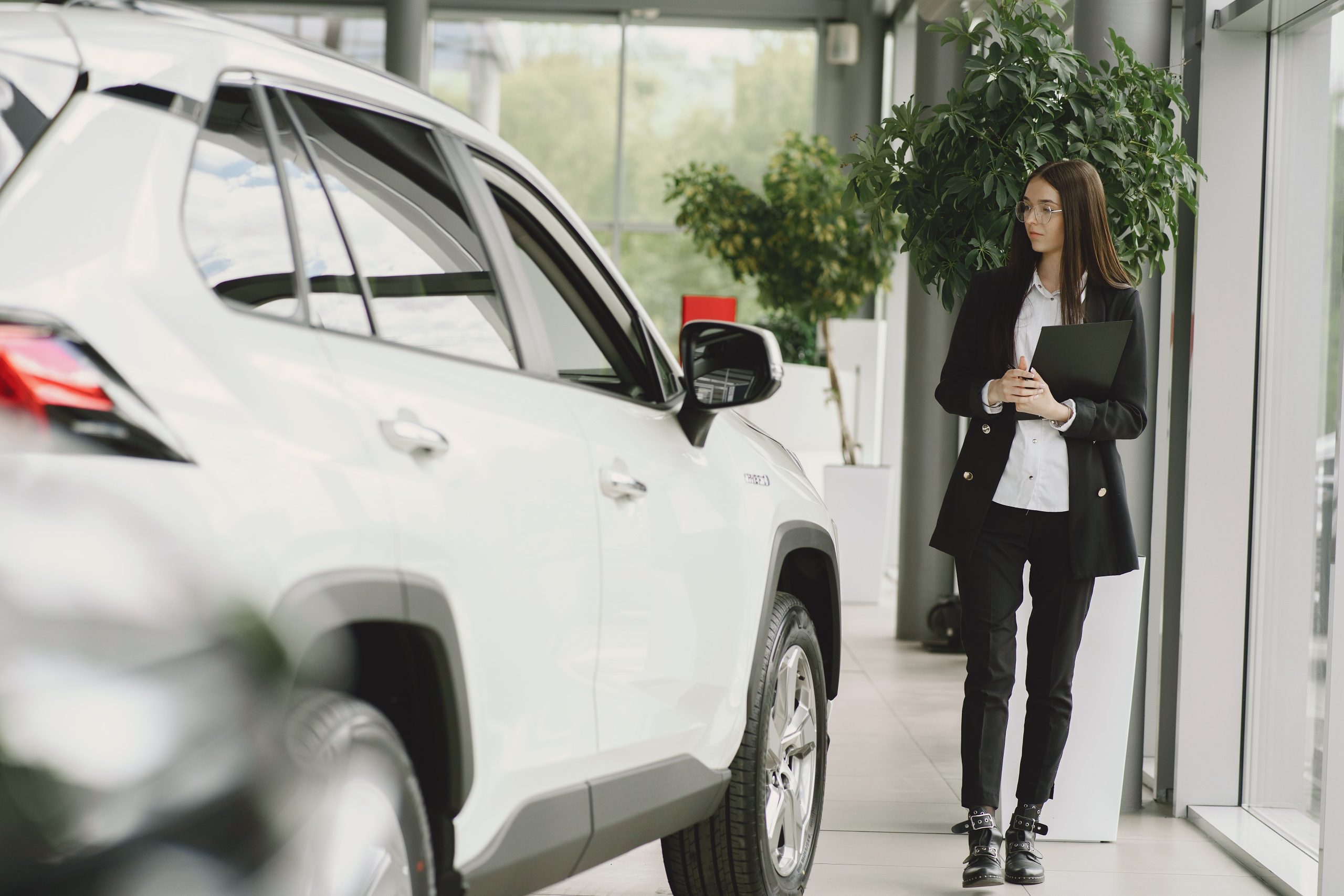 Femme d'affaires inspectant une voiture en concession