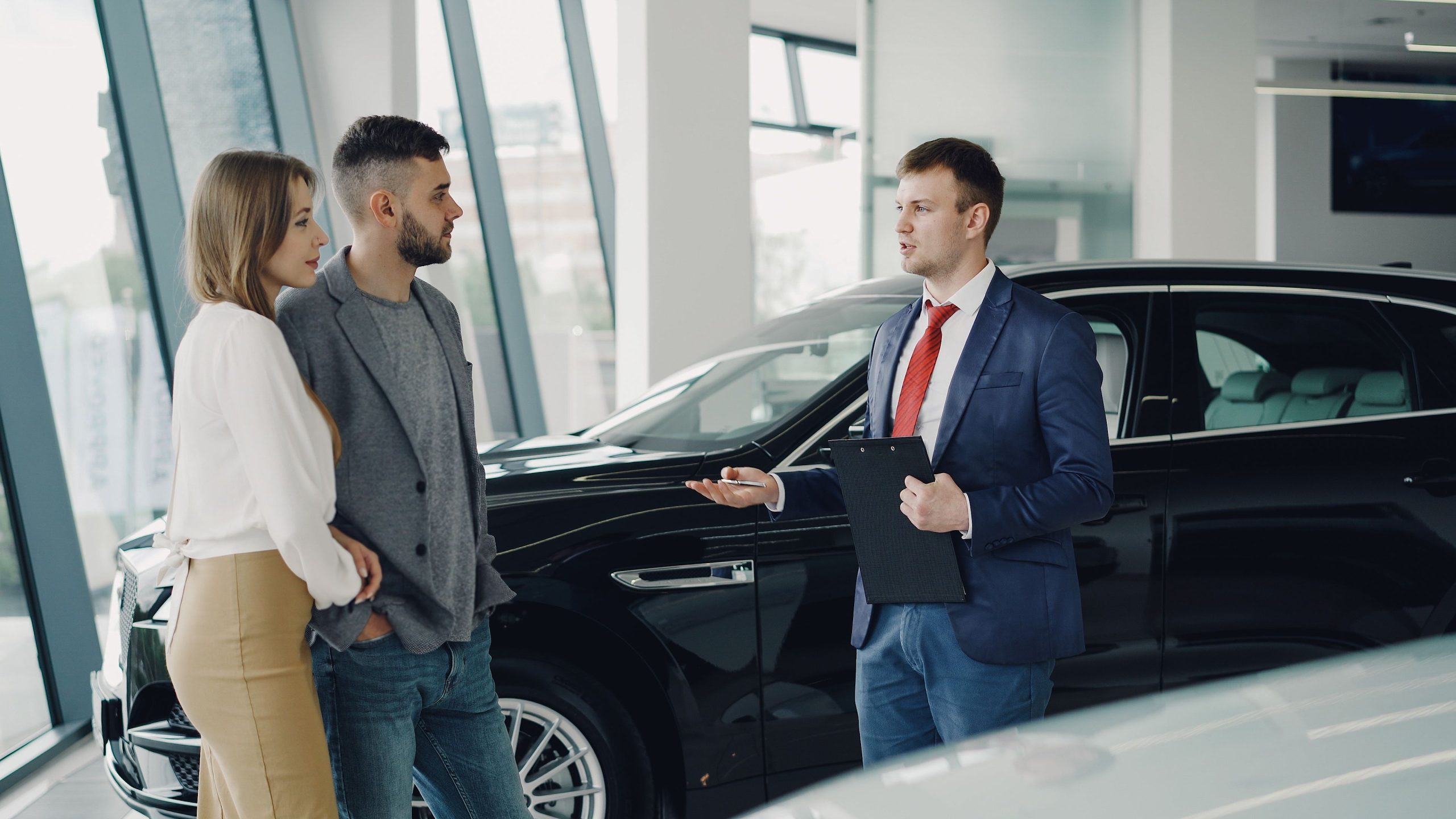 Couple discute avec vendeur concession automobile